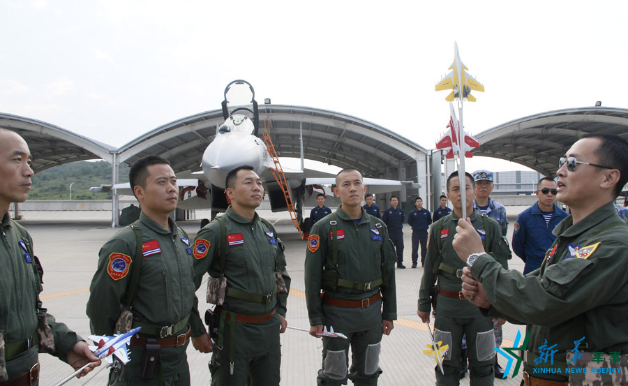 ↑舰载航空兵某部司令员戴明盟向飞行员演示空中飞行注意事项。